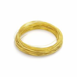 May include: A coil of gold-colored wire, likely for jewelry making or crafts, is displayed against a white background. The wire is tightly wound, showcasing its flexibility and potential for various creative projects. The bright, metallic hue suggests a high-quality material.