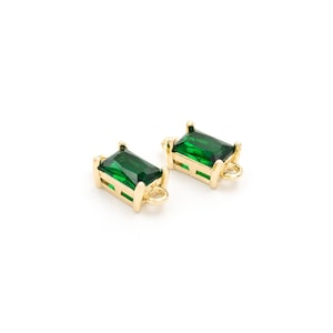 Pode incluir: Dois pingentes de conexão de metal dourado com pedras preciosas retangulares de cor verde esmeralda. Os pingentes têm um laço em um lado para prender em joias.