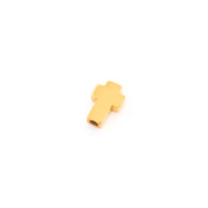 Peut inclure: Un petit pendentif en forme de croix de couleur or. La croix a un design simple et classique avec des bords arrondis et un trou pour l'enfilage. Le pendentif est posé sur un fond blanc uni.