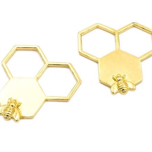 May include: Two gold-toned metal honeycomb charms with a bee design. Each charm features three hexagonal shapes, two of which are open.