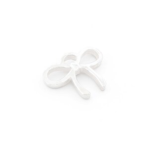 May include: A silver charm in the shape of a bow.