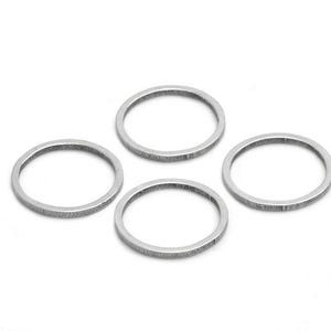 Könnte beinhalten: Vier dünne, kreisförmige Metallringe in Silberoptik, die in einer Gruppe angeordnet sind. Jeder Ring weist eine texturierte, gebürstete Oberfläche auf, die ein dezentes mattes Aussehen erzeugt. Die Bänder haben eine gleichmäßige Dicke und Form.