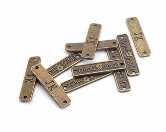 0.31 EUR/pc. Connector patches with inscription in antique bronze color 10 pieces