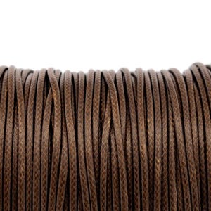 May include: A spool of dark brown cord featuring a tightly woven, braided texture. The individual strands are arranged in parallel vertical lines, creating a uniform and consistent pattern across the entire surface of the cylindrical spool.