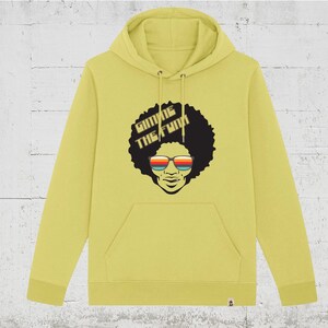 Könnte beinhalten: Ein gelber Hoodie mit einer Schwarz-Weiß-Illustration einer Person mit Afro, die eine Sonnenbrille trägt. Der Text "Gimme the Funk" ist auf dem Hoodie aufgedruckt.