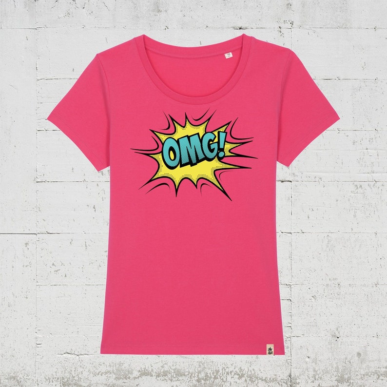 Pode incluir: Uma camiseta rosa com um gr&aacute;fico de estilo de banda desenhada amarelo e azul que diz "OMG!"