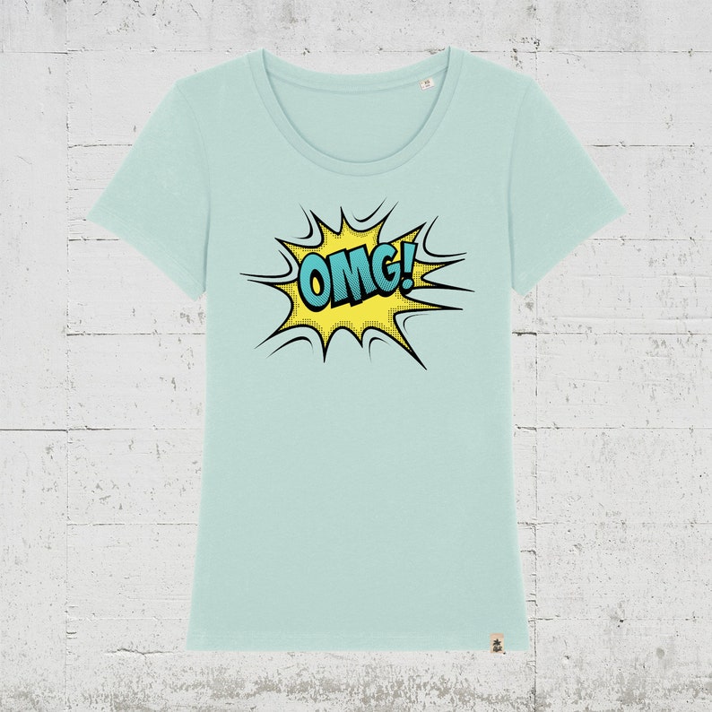 Pode incluir: Uma camiseta azul claro com um gr&aacute;fico de estilo de banda desenhada amarelo e azul que diz "OMG!"