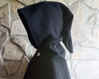 May include: A black hooded cape with a pointed hood. The cape is made of a soft, fleece-like material and has a single button closure at the neck.