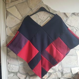 Può includere: Un poncho in patchwork blu navy, rosso e viola con un motivo a rombi.