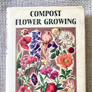 May include: Book cover with the title "COMPOST FLOWER GROWING" in black text on a white background. The cover features a colourful illustration of various flowers, including a red tulip, a purple iris, a white daisy, and a pink peony.