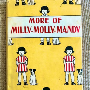 May include: A yellow book cover with the title "More of Milly-Molly-Mandy" in red and black text. The cover features illustrations of a girl wearing a red and white striped dress and a dog. The text "Told and Drawn by Joyce Lankester Brisley" is at the bottom of the cover.