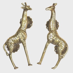 May include: Two brass giraffe-shaped door handles. The giraffes have a detailed spotted pattern and are mounted on decorative floral backplates. The handles are in a standing position, with their long necks and legs extended.