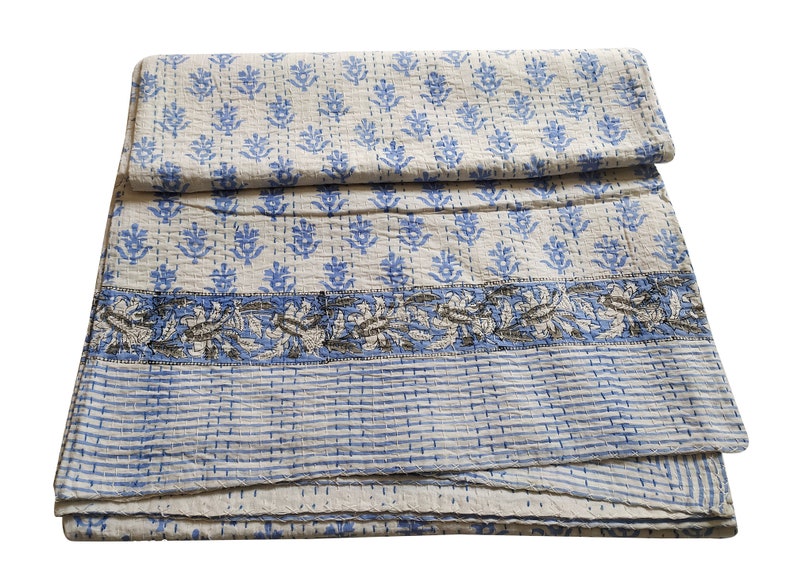 May include: A white and blue kantha quilt with a floral pattern. The quilt is folded in half and has a striped border.
