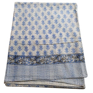 May include: A white cotton quilt with a blue floral pattern and a blue and gray border. The quilt is folded in thirds and is lying on a white background.