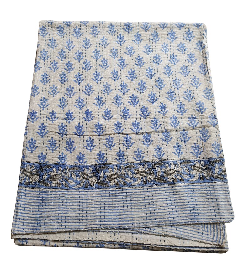 May include: A white cotton quilt with a blue floral pattern and a blue and gray border. The quilt is folded in thirds and is lying on a white background.