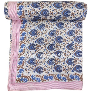 May include: A white cotton quilt with a blue and brown floral pattern. The quilt has a pink and white striped border. The quilt is rolled up and the text "KanthaNTapestryArt" is visible.