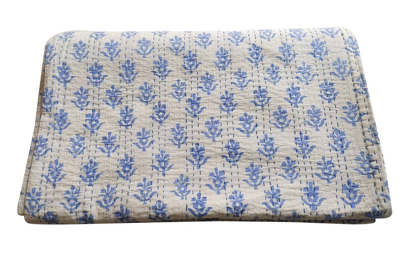 May include: A white cotton quilt with a blue floral pattern. The quilt is folded in half and has a subtle texture.