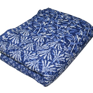 May include: A blue and white kantha quilt with a floral pattern. The quilt is folded in half and is made of cotton.