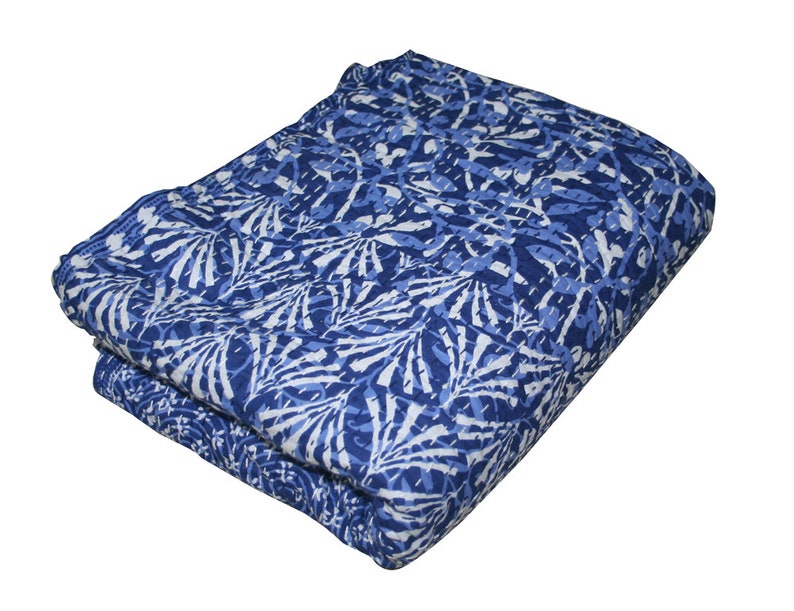 May include: A blue and white kantha quilt with a floral pattern. The quilt is folded in half and is made of cotton.