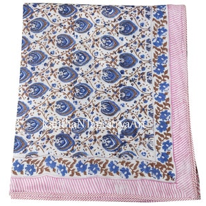 May include: White cotton throw blanket with a blue and brown floral pattern. The blanket has a pink and white striped border.