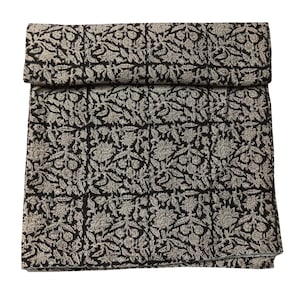 May include: Black fabric with a white floral pattern. The fabric is folded in half and has a smooth texture.