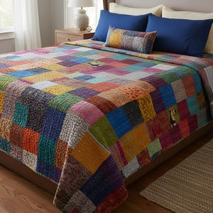 May include: A colourful patchwork quilt on a bed. The quilt displays a variety of patterns and colours, including squares of blue, green, orange, and pink. The bed is made with blue pillows and a decorative bolster pillow.