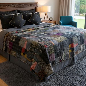 Peut inclure: Un lit est fait avec une courtepointe patchwork dans les tons de noir, gris et d'autres couleurs. Le lit a des oreillers noirs avec des accents dorés. Une tête de lit en bois et un jupon de lit gris complètent le look. Une petite lampe de chevet et une chaise bleue sont également visibles.