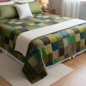 Peut inclure: Un lit avec une courtepointe patchwork aux tons de vert, bleu et marron. La courtepointe présente un motif carré et est assortie d'oreillers verts et blancs. Une couverture blanche est drapée sur le lit.