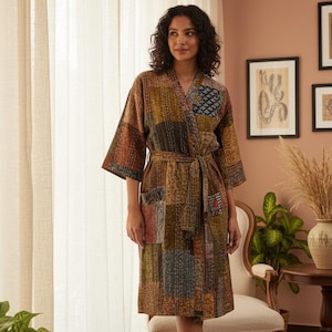 Könnte beinhalten: Patchwork-Robe in Braun-, Grün- und Blautönen. Die Robe hat einen Bindegürtel und Taschen. Die Person trägt die Robe in einem Raum mit Teppich, Stuhl und Pflanzen.