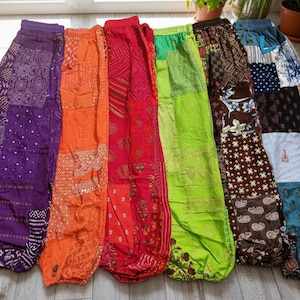 以下が含まれることがあります： 紫、オレンジ、赤、緑、茶色など、さまざまな色合いのカラフルな柄入りハーレムパンツのコレクション。 各ペアはユニークなパッチワークデザインと伸縮性のあるウエストバンドを備えています。 パンツは軽量生地で作られています。