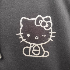 May include: A silver glitter Hello Kitty design on a black background. The design features Hello Kitty with a bow and winking.
