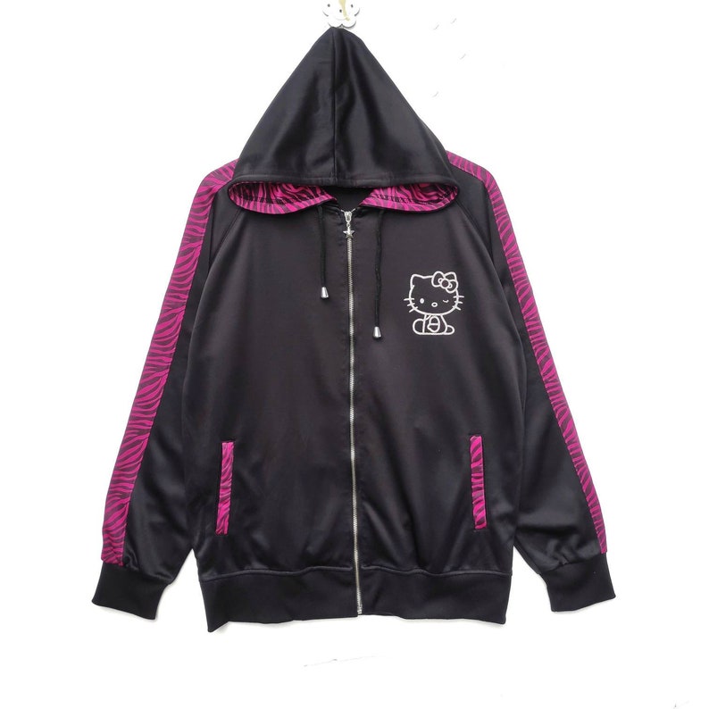 May include: Black zip-up hoodie with pink zebra print on the sleeves and a white Hello Kitty graphic on the front.