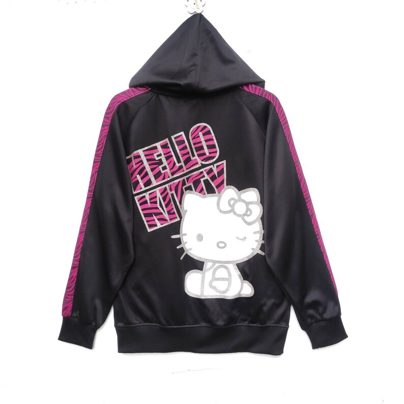 May include: Black zip-up hoodie with pink and black zebra print stripes on the sleeves. The hoodie has a Hello Kitty graphic with the text "Hello Kitty" in pink and black zebra print letters.