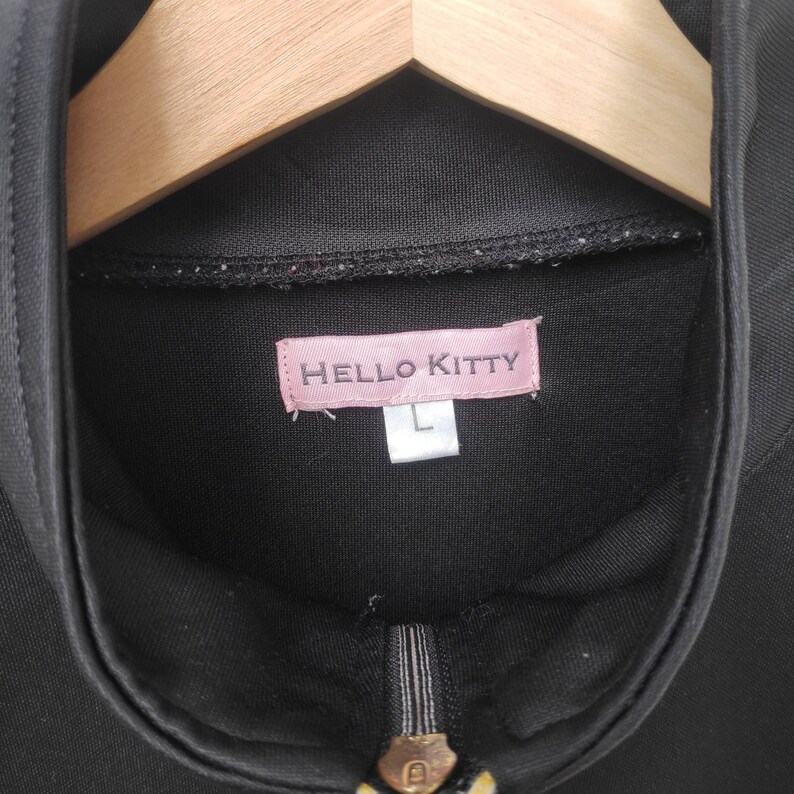 May include: Black zippered jacket with a pink Hello Kitty label and a size L tag.