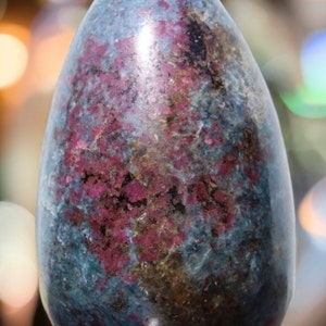 Könnte beinhalten: Ein großer, polierter, blauer und rosafarbener eiförmiger Edelstein auf einem goldenen Sockel. Der Edelstein hat eine marmorierte Optik mit rosa und blauen Farbtönen.