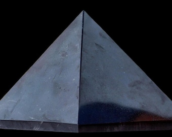 May include: A solid, dark gray, four-sided pyramid with a smooth, polished surface. The object features sharp, clean edges meeting at a single apex point, with a flat, square base resting on a surface. The material appears dense and opaque.