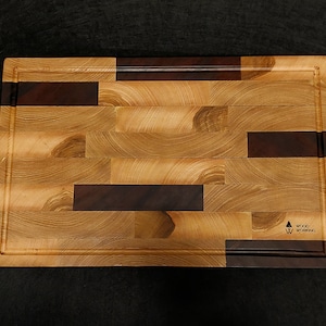 Może przedstawiać: Prostokątna drewniana deska do krojenia z wzorem z jasnego i ciemnego drewna. Deska ma podniesiony brzeg i logo z napisem "Woodworking" w prawym dolnym rogu.