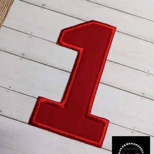 May include: Red felt number one with a white background. The number is outlined in red thread.