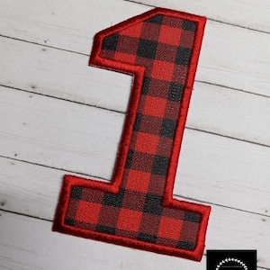 May include: Red and black buffalo plaid fabric number one with a red stitched border.
