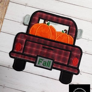 Puede incluir: Camioneta roja a cuadros con una puerta trasera que dice "Fall" y está llena de calabazas naranjas.