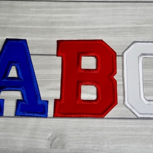 May include: Three felt letters, A, B, and C, in blue, red, and white, respectively. The letters are in a varsity style font and have a raised, 3D effect.