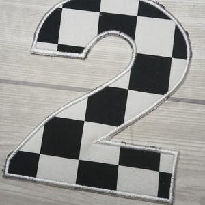 May include: A black and white checkered number two patch with a white stitched border.