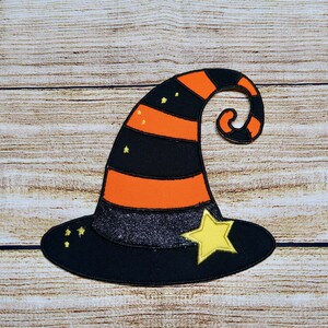 May include: A black and orange witch hat with a curled brim and a yellow star on the front. The hat is decorated with small yellow stars.