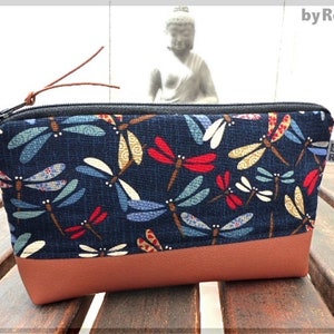 May include: A blue zippered pouch with a brown leather bottom. The pouch is decorated with a repeating pattern of colorful dragonflies. The text "by Rossi" is printed on the side of the pouch.