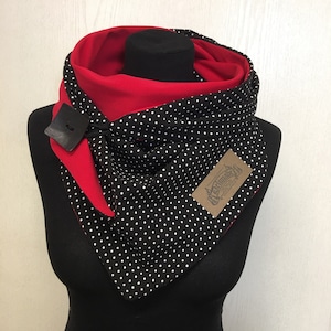 Könnte beinhalten: Ein schwarz-weiß gepunkteter Schal mit rotem Futter. Der Schal hat ein braunes Leder-Etikett mit dem Text "Handmade Design". Der Schal befindet sich auf einer schwarzen Puppe.