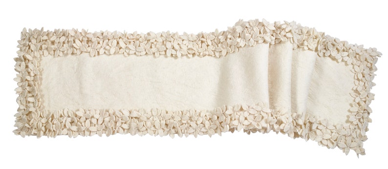 May include: A cream-colored table runner with a decorative border of small, flower-shaped embellishments.