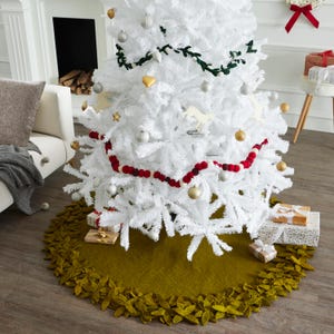 May include: A green felt Christmas tree skirt with a leafy trim. The skirt is decorated with a white and red beaded garland and a white Christmas tree with gold and silver ornaments.