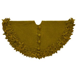 May include: A mustard yellow felt Christmas tree skirt with a scalloped edge and a row of felt leaves around the perimeter. The skirt has four decorative buttons down the center.