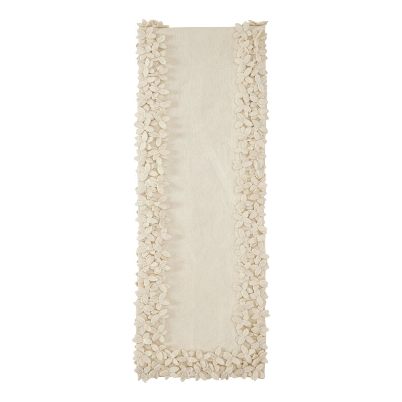 May include: A cream-colored table runner with a raised floral design around the edges.