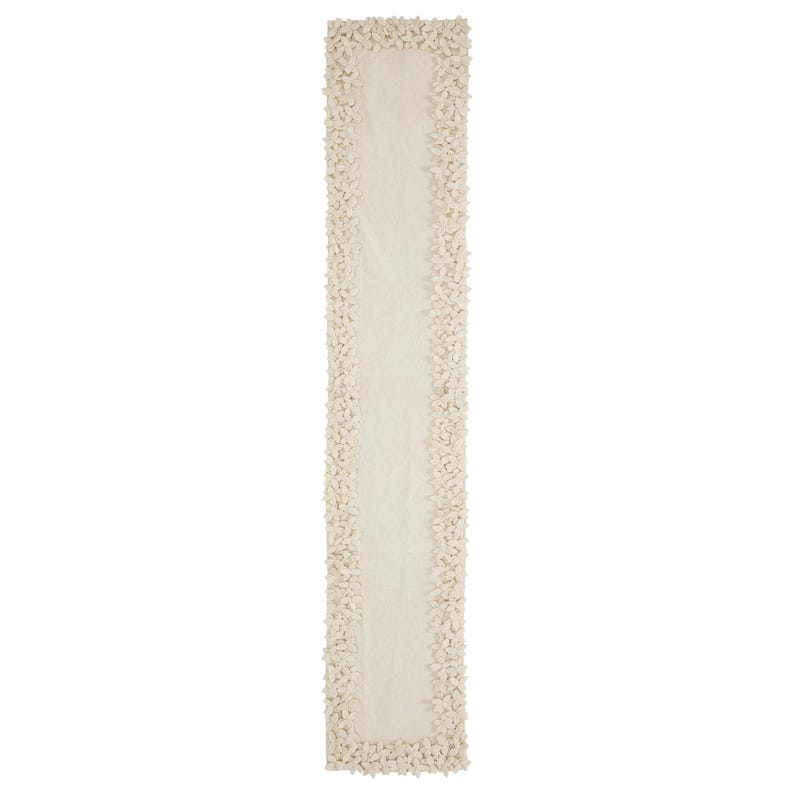 May include: A white table runner with a textured, floral design along the edges.
